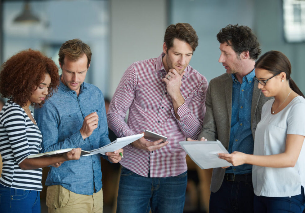 Colleagues talking about paperwork while standing in the office together.