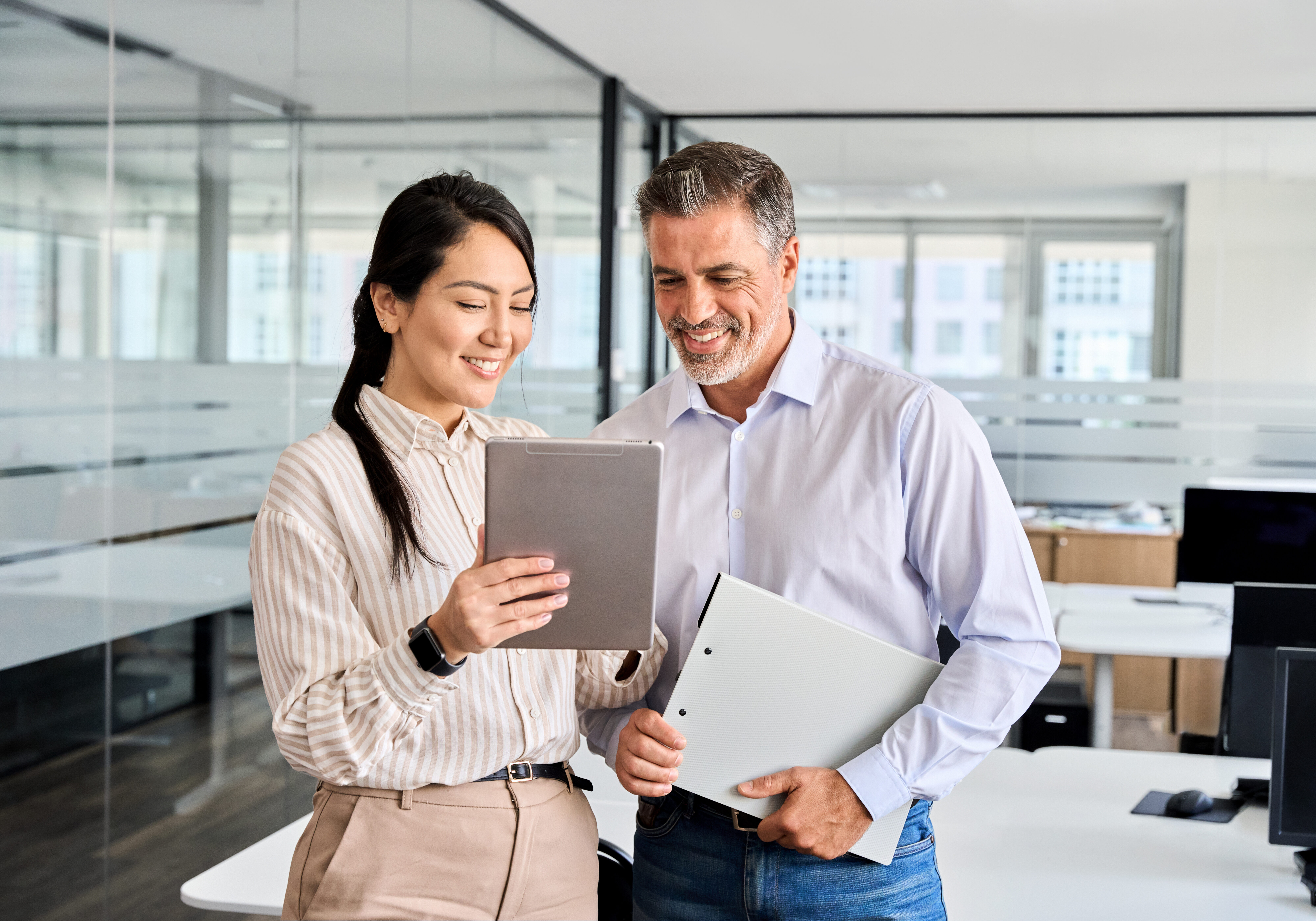 Two happy professional business people workers using digital tablet in office.